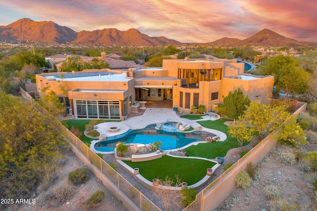 back house at dusk featuring a mountain view and a patio