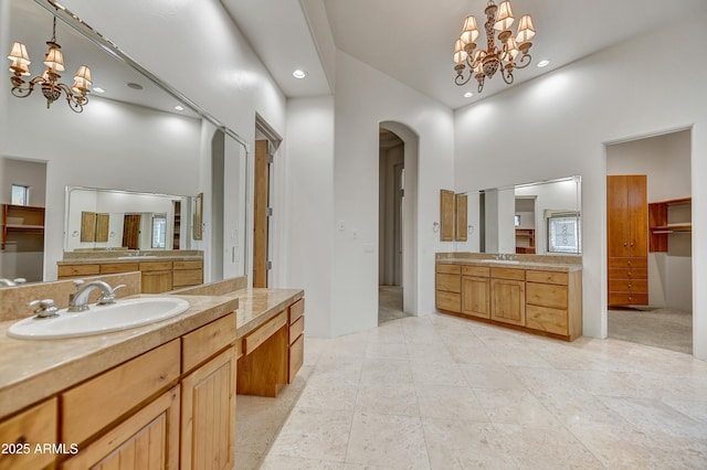 bathroom featuring an inviting chandelier, vanity, and a high ceiling