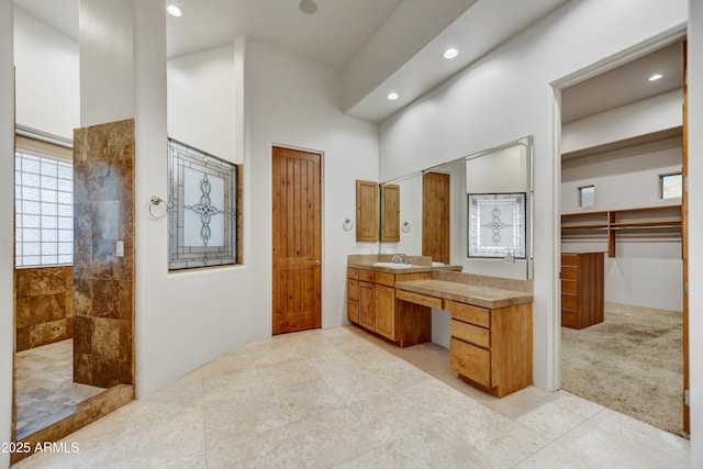 bathroom with vanity, a towering ceiling, and tiled shower