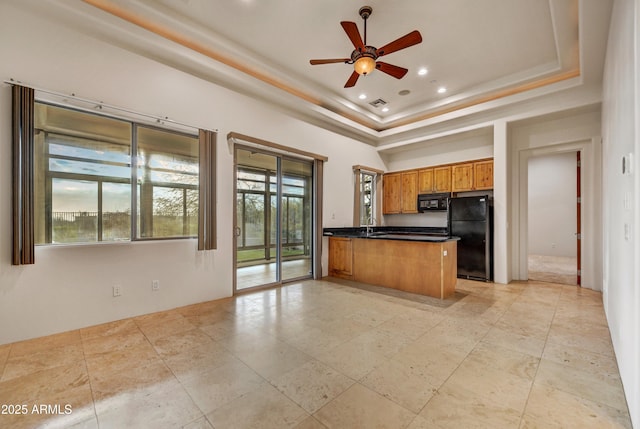 kitchen featuring ceiling fan, a towering ceiling, a tray ceiling, black appliances, and kitchen peninsula