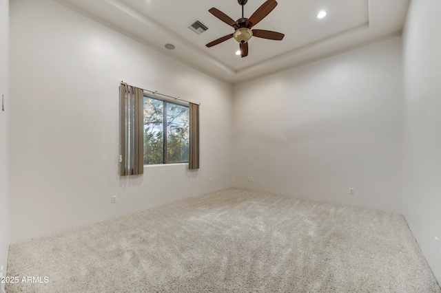 unfurnished room with ceiling fan, a tray ceiling, and carpet floors