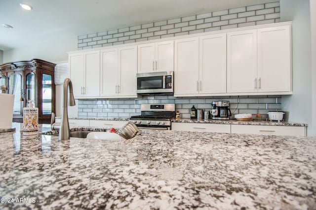 kitchen featuring light stone countertops, appliances with stainless steel finishes, sink, and white cabinets