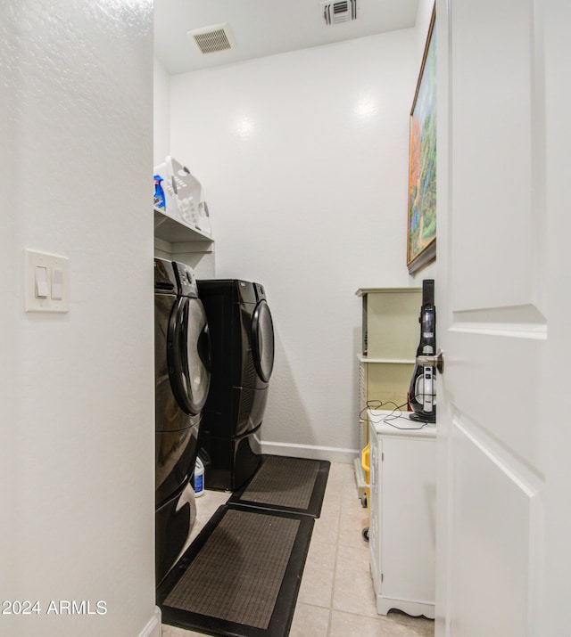 clothes washing area with light tile patterned floors and washer and clothes dryer