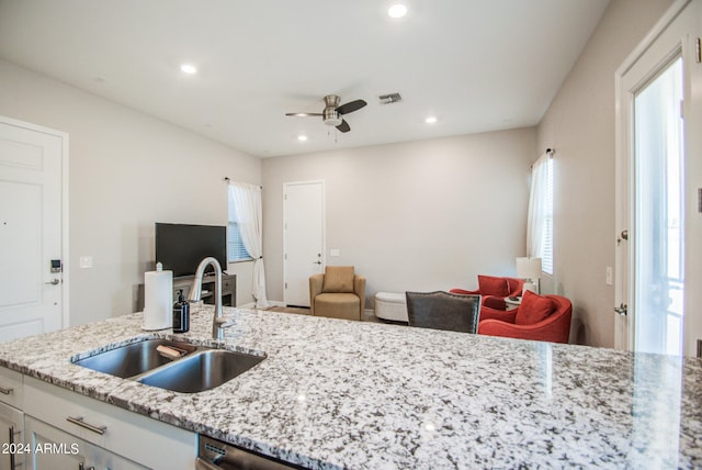 kitchen with white cabinetry, light stone counters, a healthy amount of sunlight, and sink