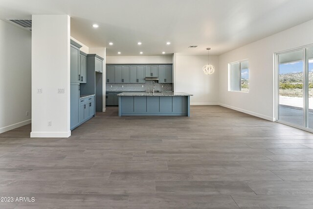 kitchen with baseboards, open floor plan, decorative backsplash, and an island with sink