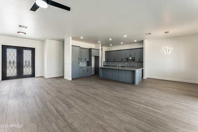 kitchen featuring decorative backsplash, french doors, visible vents, wood finished floors, and open floor plan