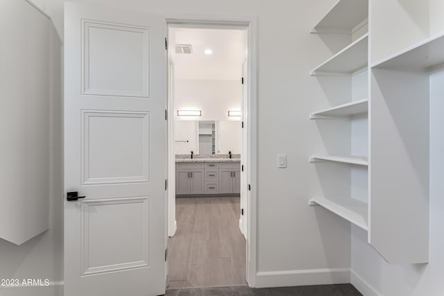 walk in closet featuring visible vents, a sink, and wood finished floors