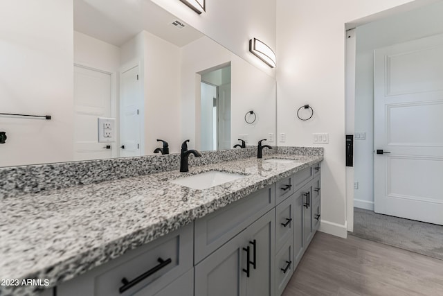 full bath with double vanity, visible vents, a sink, and wood finished floors