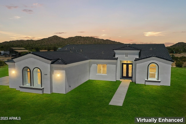 rear view of property with a mountain view, stucco siding, and a yard