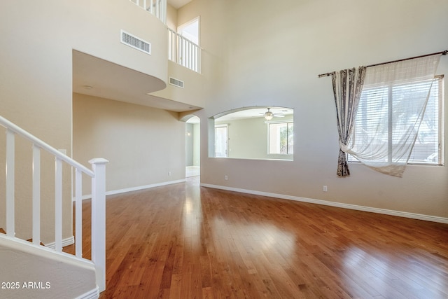 unfurnished living room featuring a high ceiling, ceiling fan, and hardwood / wood-style flooring