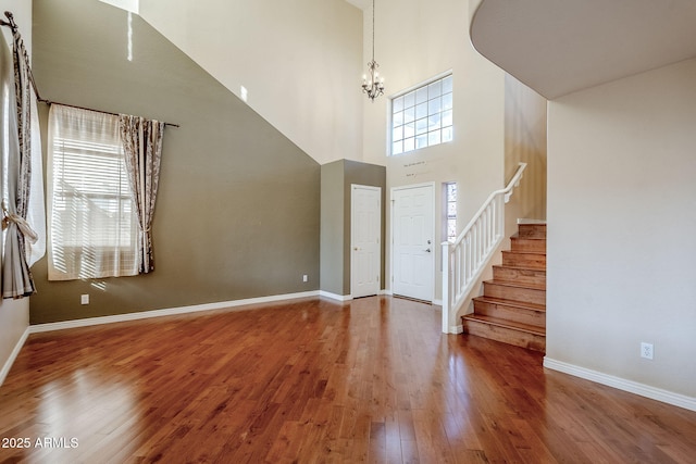 foyer entrance featuring a towering ceiling, hardwood / wood-style flooring, and a notable chandelier