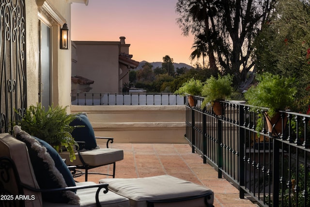 patio terrace at dusk featuring a balcony