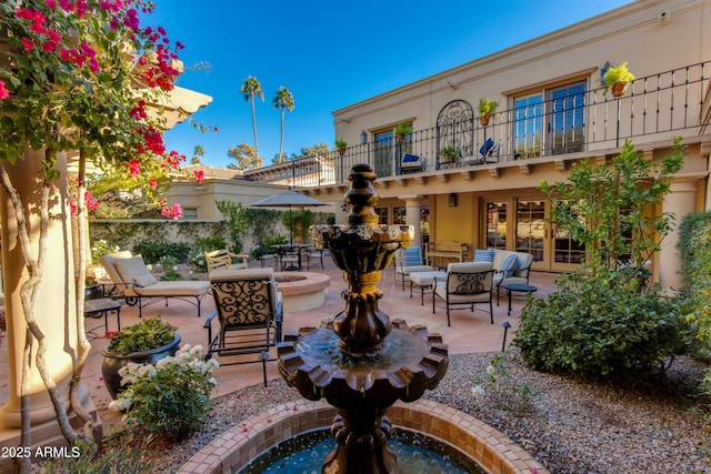 view of patio with a balcony and an outdoor fire pit