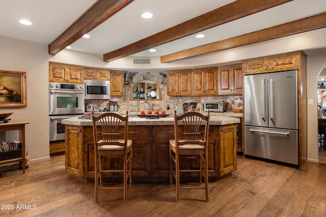 kitchen with stainless steel appliances, a breakfast bar area, a center island, and hardwood / wood-style floors