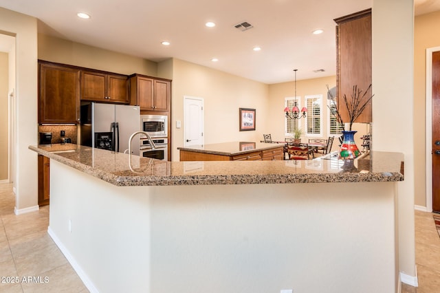 kitchen featuring appliances with stainless steel finishes, a center island, light tile patterned floors, and kitchen peninsula