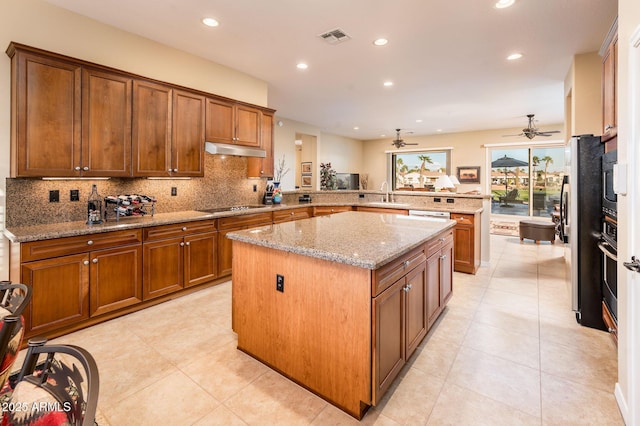 kitchen featuring tasteful backsplash, a center island, kitchen peninsula, stainless steel appliances, and light stone countertops