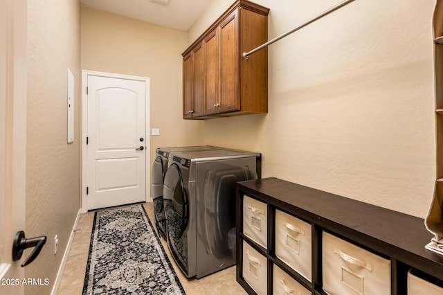 laundry room with light tile patterned floors, cabinets, and washing machine and clothes dryer