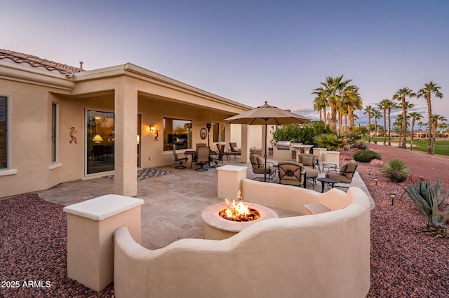 patio terrace at dusk with an outdoor living space with a fire pit