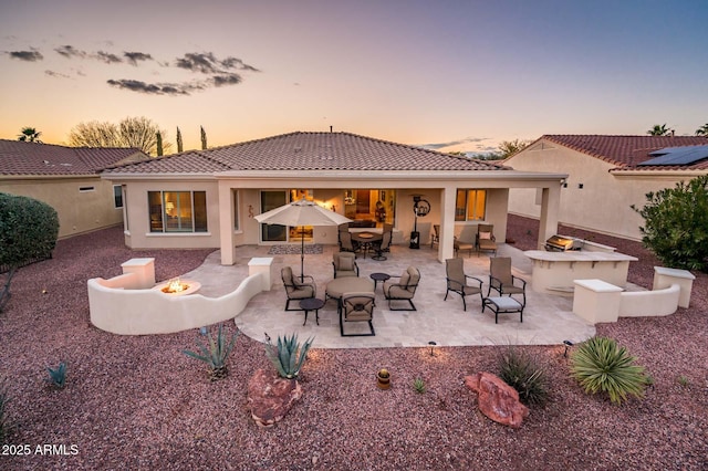 back house at dusk with a fire pit and a patio