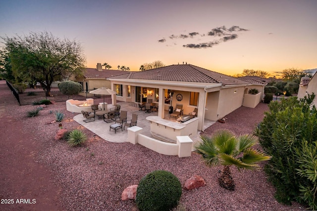 back house at dusk with a patio area