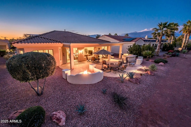 back house at dusk with a patio and a fire pit