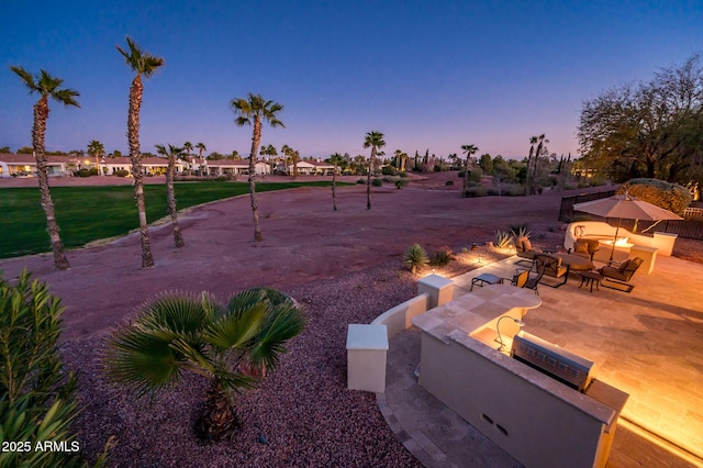 yard at dusk featuring a patio area and a fire pit