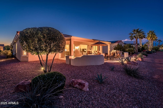 back house at dusk featuring a patio area and outdoor lounge area