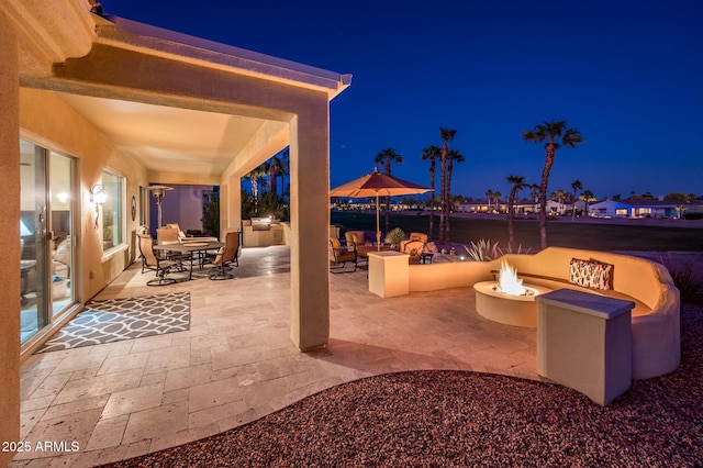 patio at twilight featuring an outdoor kitchen and an outdoor fire pit