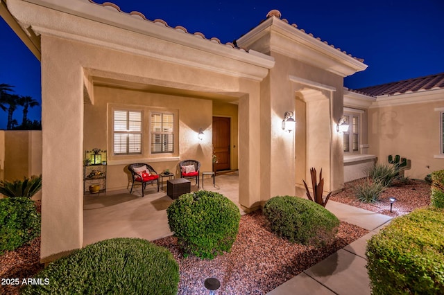 exterior entry at twilight featuring a patio area