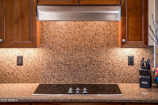 room details featuring black electric stovetop, ventilation hood, decorative backsplash, and dark stone counters