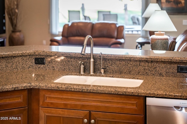 room details featuring stainless steel dishwasher, light stone countertops, and sink