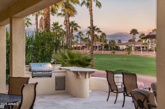 patio terrace at dusk featuring a grill, area for grilling, and a yard