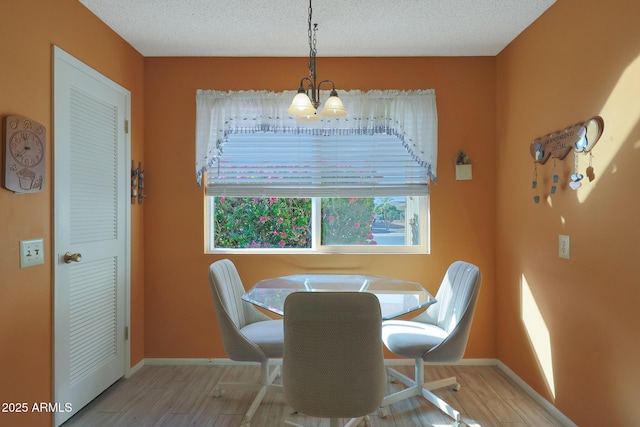 dining area featuring light hardwood / wood-style floors, a textured ceiling, and a notable chandelier