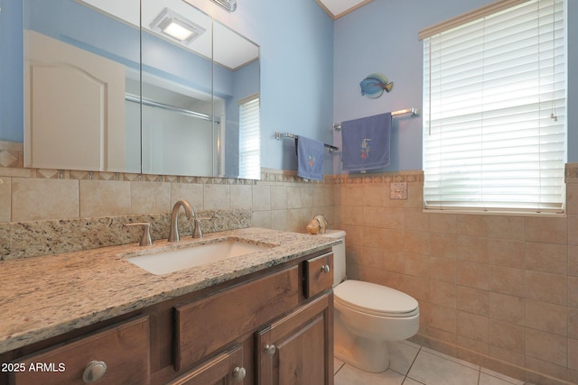 bathroom with tile patterned floors, vanity, tile walls, and toilet