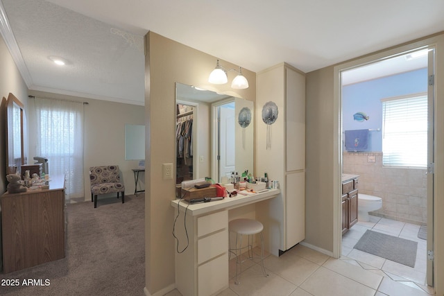 bathroom with tile patterned floors, crown molding, toilet, vanity, and tile walls