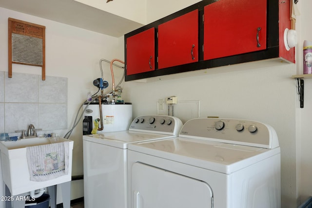 laundry area featuring washer and dryer, cabinets, sink, and gas water heater