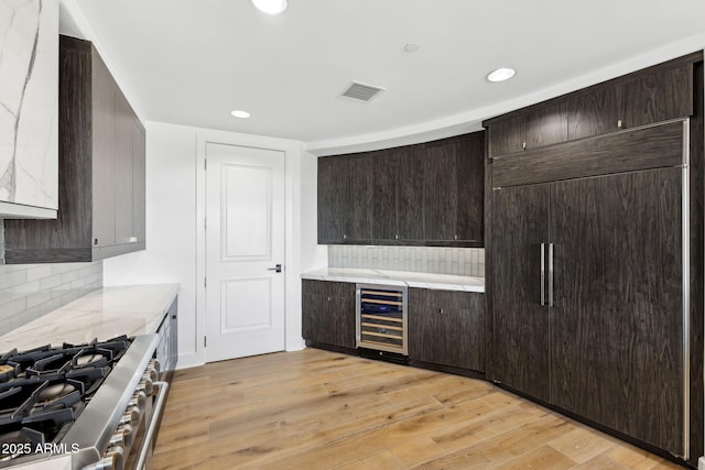 kitchen with high quality appliances, dark brown cabinets, wine cooler, and visible vents