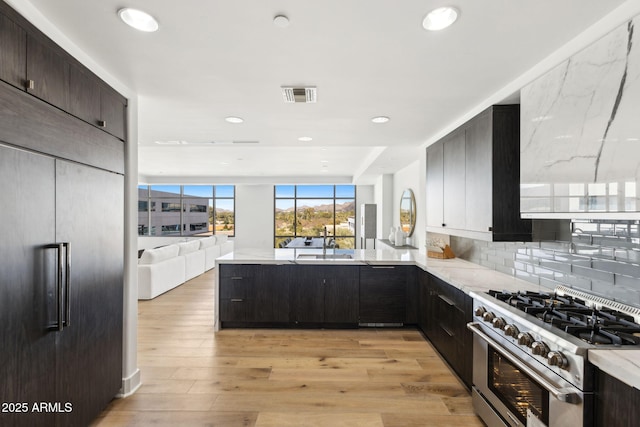 kitchen with stainless steel range, light wood finished floors, visible vents, open floor plan, and a sink