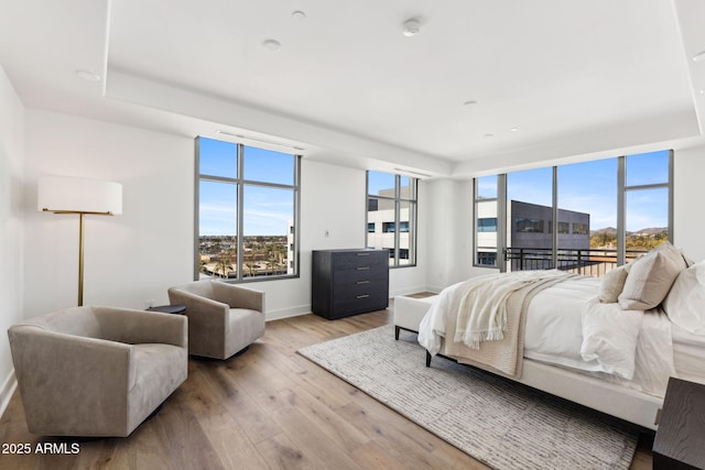 bedroom with access to outside, multiple windows, baseboards, and wood finished floors