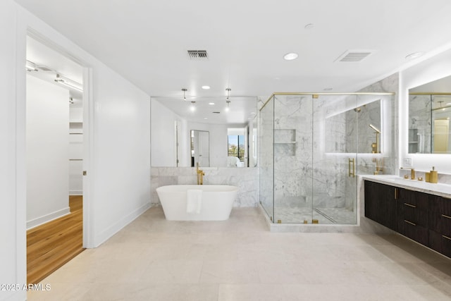 bathroom with a freestanding tub, visible vents, vanity, and a marble finish shower