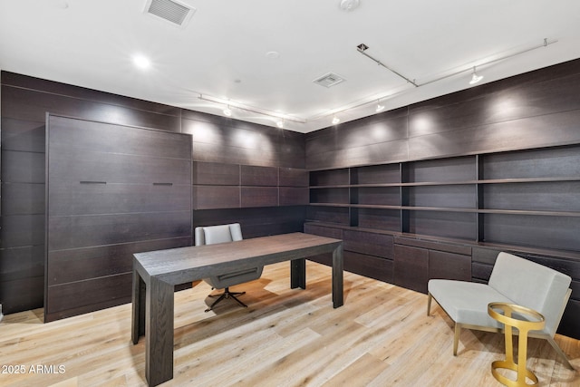 home office with light wood-style floors, rail lighting, and visible vents