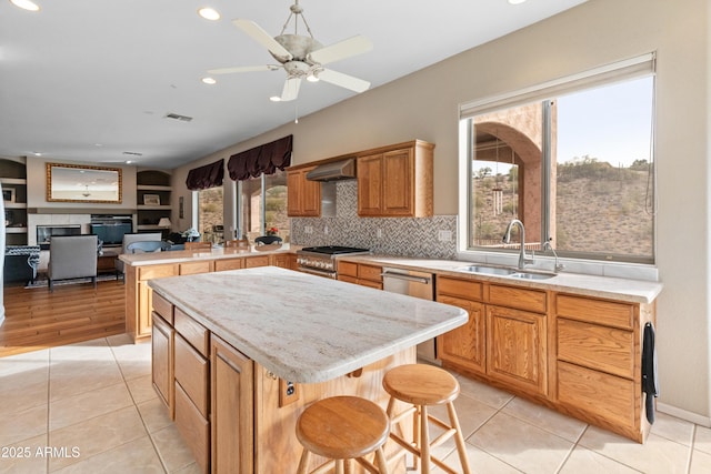 kitchen with a kitchen breakfast bar, a center island, light tile patterned floors, and range hood