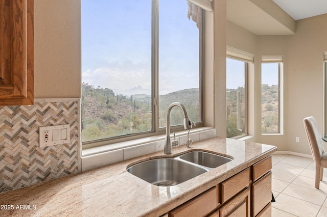 kitchen featuring light stone countertops, sink, light tile patterned floors, and a mountain view