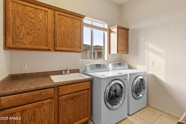 laundry area with washer and dryer, light tile patterned floors, cabinets, and sink