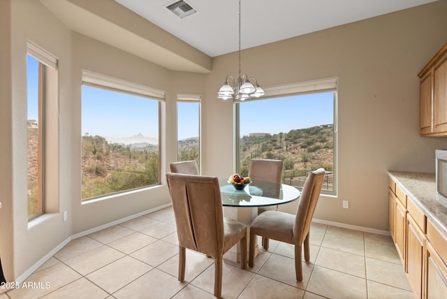 dining area with a mountain view, light tile patterned floors, and an inviting chandelier