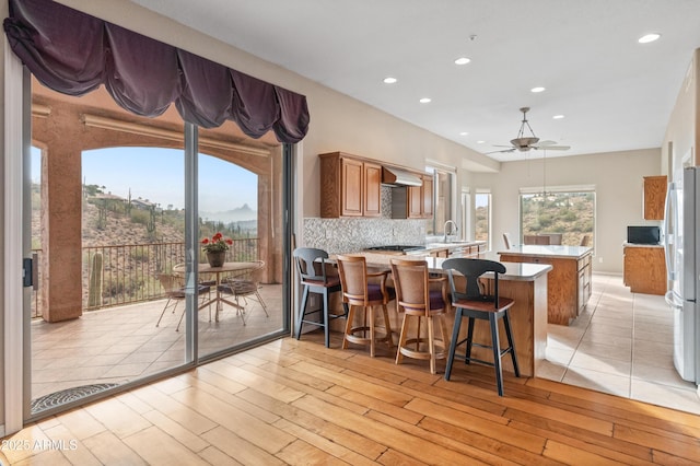 kitchen with appliances with stainless steel finishes, light hardwood / wood-style floors, kitchen peninsula, and extractor fan