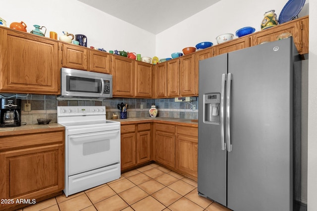 kitchen with tile countertops, light tile patterned flooring, tasteful backsplash, and stainless steel appliances