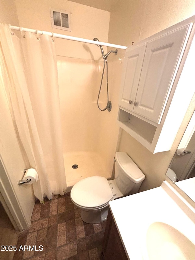 bathroom featuring toilet, a stall shower, visible vents, and vanity