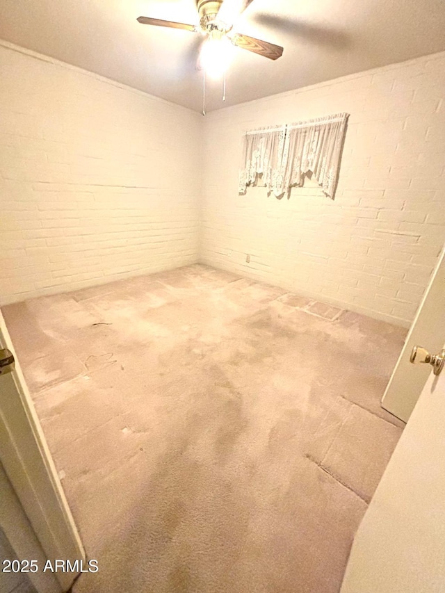 spare room featuring carpet floors, brick wall, and a ceiling fan