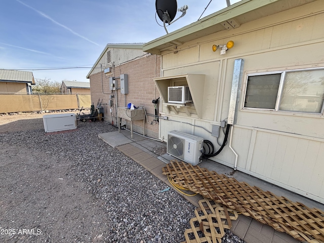 view of side of home with ac unit and fence